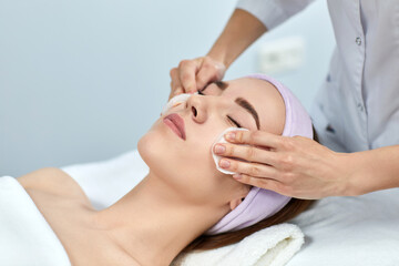 Fototapeta na wymiar beautician cleanses female skin with a sponge. Perfect cleaning, spa treatment skincare face.