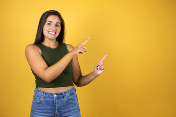 Young beautiful woman standing over yellow isolated background smiling and pointing his fingers