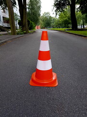 orange traffic cone placed in city street, warning sign on road