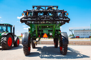 Fototapeta premium Professional modern tractor, combine at a field in sunlight at work. Vibrant, bright summer colors. Agriculture, exhibition, machinery, plant production. Modern machines at work process.