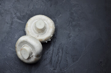 Fototapeta na wymiar Raw champignon mushrooms on dark background. Vegan food concept.