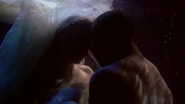 passion of two lovers underwater, tender woman and excited man are kissing and embracing