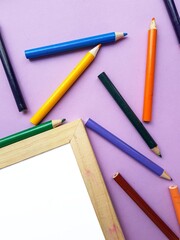 Empty clean white sheet for the buyer's text on the purple background and school supplies, pencils. Back to school.