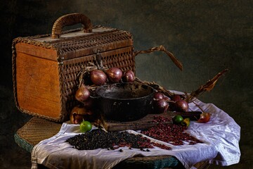 Rattan picnic basket with a small cauldron red onions and red and black beans on round rattan table