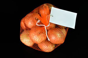 Onions in net bag with tag isolate on black background