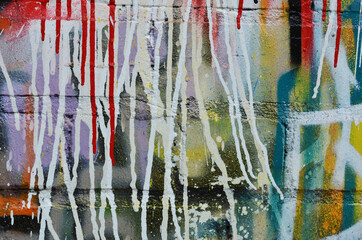 Red and white streaks of paint flow down an old multi colored brick wall