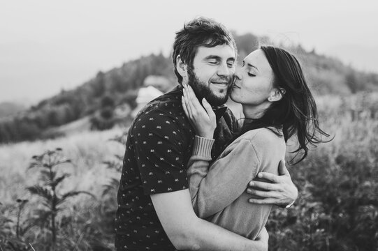 Couple travelers. Man and woman kissing on the background on mountains. Love and travel, happy emotions. Lifestyle concept. Portrait of a happy couple laughing at camera. Black and white photo.