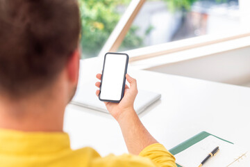 Cropped shot of a man using a smartphone while sitting at office desk