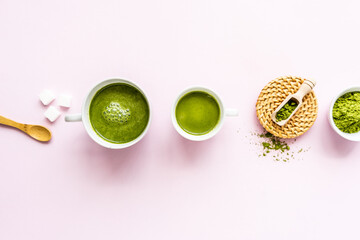 Matcha Latte, zwei weiiße Tassen und Zutaten in einer Reihe auf einem rosa Hintergrund. Flat lay,...