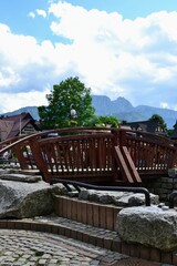 Fototapeta na wymiar Zakopane, Poland. View from Krupowki street. Small wooden bridge and Tatra Mountains view (Giewont summits). Summer day