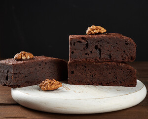 stack of baked pieces of brownie chocolate cake with nuts on a wooden board