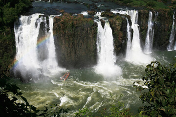 Obraz premium A tourist boat approaches the bottom of Iguazu Falls. Foz do Iguaçu, Brazil.