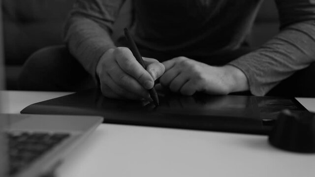 Graphic designer using electronic drawing tablet at home.