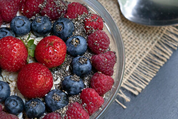 Set of summer berries with oatmeal in a small glass bowl on a napkin and wooden background. Perfectly healthy summer breakfast. Super.