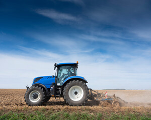 farmer in tractor with harrow on field in the north of france