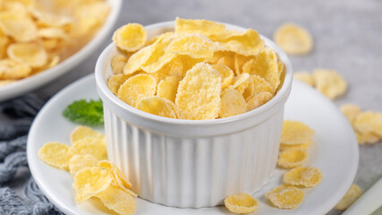 Corn flakes bowl sweeties with milk on gray cement background, close up, fresh and healthy breakfast design concept.