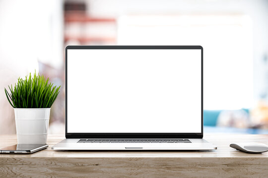 Laptop with blank screen on white table with mouse and smartphone. Home interior or office background