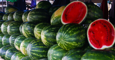 rows of watermelons and sliced watermelon on food market