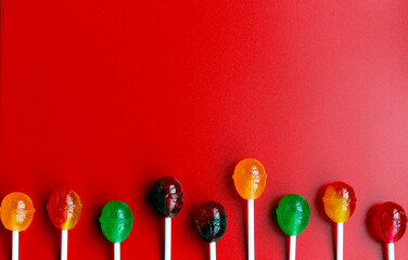 Red background with multicolored round lollipops in the corners. Red background with chupa chups