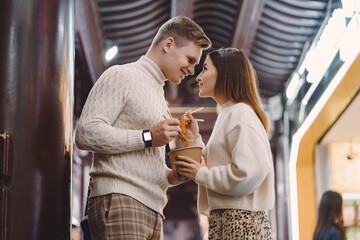 newlywed couple eating noodles with chopsticks in Shanghai outside a food market near Yuyuan. Couple eating authentic local food. husband and wife eating chinese food outisde of a food hall