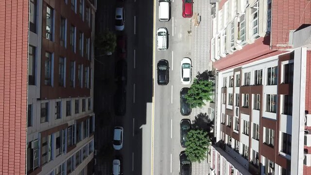 Aerial view of the city traffics at the center. Vehicles are moving on the road between buildings. 