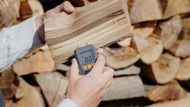 The owner of the fireplace checks the humidity of the firewood before kindling the fireplace