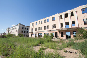 Abandoned ruined buildings on a vacant lot in a small semi-deserted city.