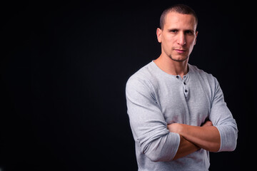 Muscular man with arms crossed against black background