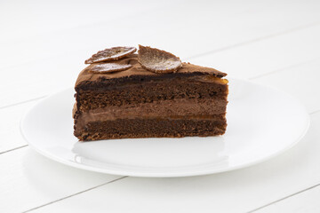 Piece of chocolate homemade cake with nuts and apricot jelly in a plate