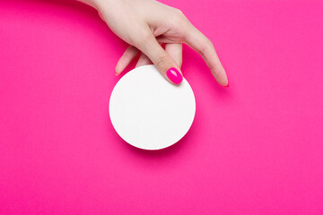 Obraz na płótnie Canvas Female hand holds one round empty coasters on pink background