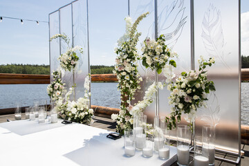 Side view of wedding ceremony with white transparent screens and fresh white flowers and candles