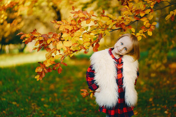 young beautiful little stylish girl in a sunny autumn park