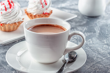 Freshly brewed aromatic coffee with cream and cake on gray background