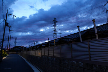 A scenic view of a pylons and houses in the shadows at night when the sun is about to set completely.