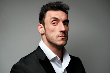 Close up portrait of a man 30-34 years old in a white shirt and a black jacket on a gray background. 