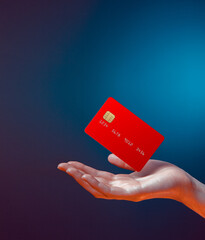 Close up female hand holds levitating template mockup Bank credit card with online service isolated on blue background - obrazy, fototapety, plakaty
