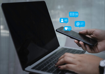 Naklejka na ściany i meble Person hand using a smartphone and laptop with social media marketing concept.