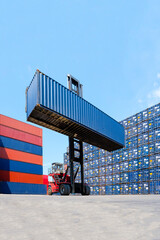 Forklift truck lifting cargo container in shipping yard or dock yard with cargo container stack in...
