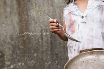 Cropped view of african american child holding metal plate and dirty spoon on urban street