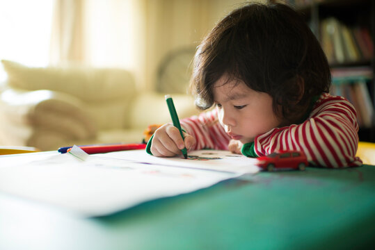 Little Asian Chinese boy child kid writing and drawing on a table. Preschooler. Early learning. Kindergarten homework. Homeschooler art class. Playschool at home. Gifted student. Homeschooling.