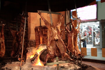 View of Argentine grilled meat Baby goat, Pork, Crosscut ribs and Rump steak on big flame of fire at a traditional Argentinean restaurant in Buenos Aires, Argentina