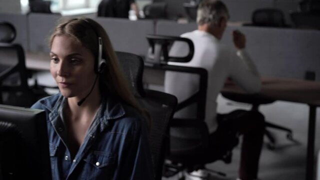 Focused male representative call center agent in wireless headset helping client with complaints using computer in office, corporate operator working in customer support service on helpline telesales