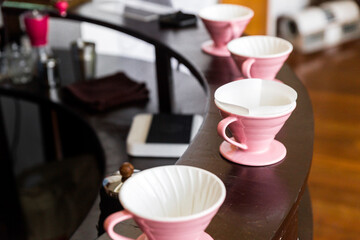Pink coffee grinder, coffee stand and pour-over on a wooden counter for making pour-over coffee with alternative method called Dripping.