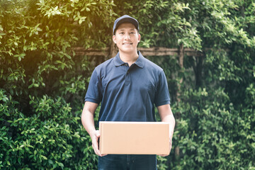 Handsome young asian delivery man smiling while holding a cardboard box delivery to his customer.