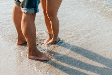 Legs of  couple stand together on beach. Man and woman in love.