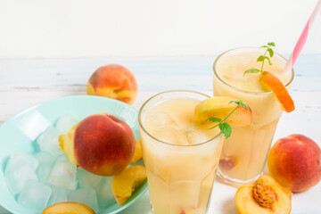 peach cold orange refreshing juice cocktail in a glass with ice and pieces of fruit and mint in the summer. top view on a light background