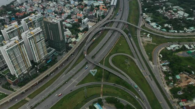 Top  down aerial view of freeway interchange with interesting looped roads and traffic. Camera pans from left to right revealing landscape