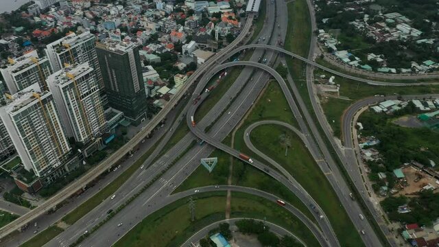 Top  down aerial view of freeway interchange with interesting looped roads and traffic. Camera pans from right to left revealing the built up landscape
