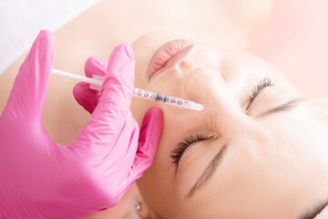 Woman getting injection procedure anti wrinkle corners of nose forehead face skin