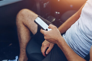 Obraz premium Photo of man hands touching phone in car. Lifestyle, travel, technology concept.